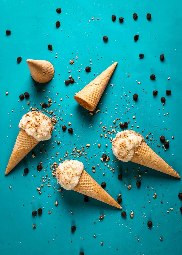 five ice cream cones with toppings on blue background
